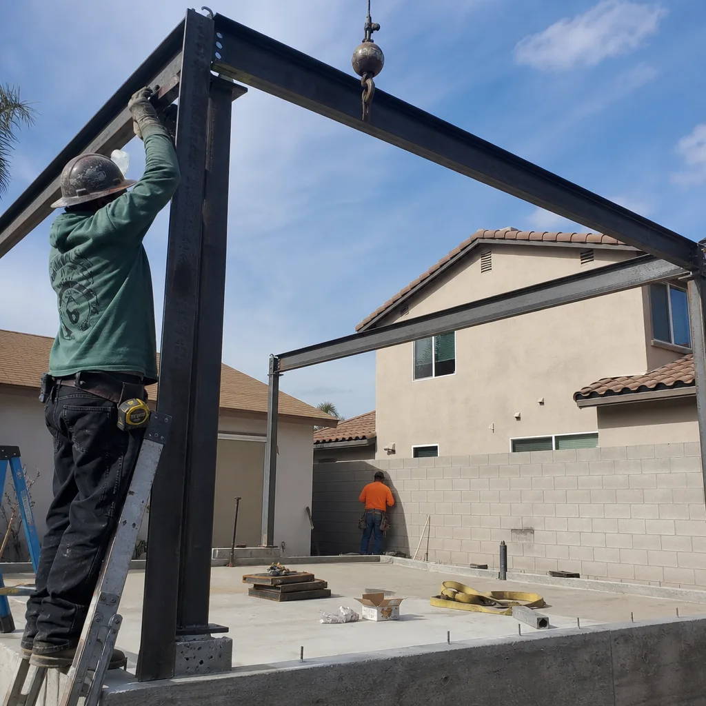 Construction workers assembling steel framing for a backyard ADU project